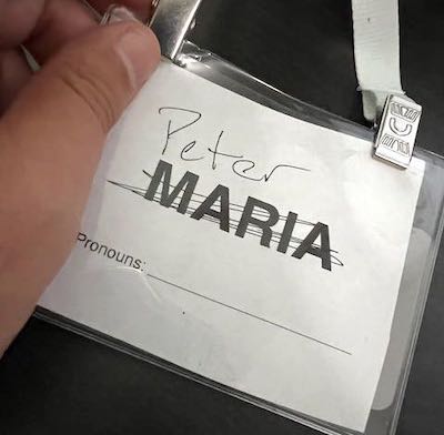 Name tag that has MARIA crossed out and PETER written in above it, and a blank line where someone could write their preferred pronouns