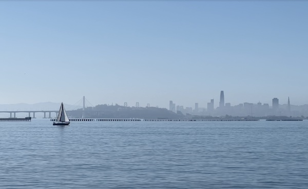 Sailboat on the San Francisco Bay on a calm and clear day, with San Francisco in the distance