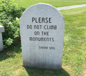 A tombstone bears the words "Please do not climb on the monuments. Thank you."