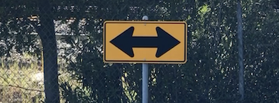 Healthy tension exists within a traffic sign at a "T" intersection with a two-headed arrow pointing left or right.