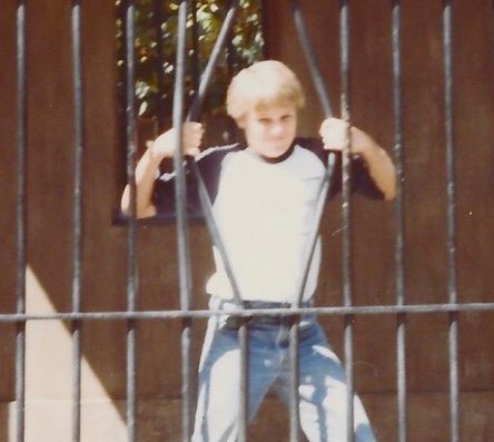 a very young Peter in a jail cell, pretending to bend the bars as if he has super strength... but he's just human