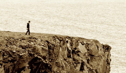 a person walks toward the edge of a cliff, metaphorically representing the identity cliff