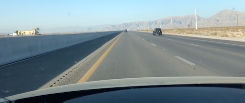 A long straight desert highway viewed from the driver's seat of a car. Metaphorical self-care steering wheel.