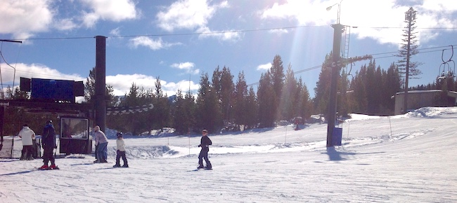 some kids at a ski resort on a sunny day, getting ready to ride the lift back to the top and have fun making new mistakes