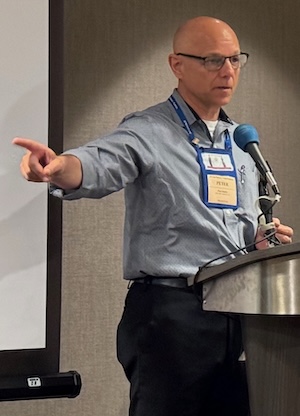 High Achiever Peter at a podium as he moderates a panel at the San Francisco Writers Conference