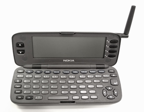 A Nokia 9000i Communicator, opened up to show the keyboard and screen, with the phone antenna raised.
