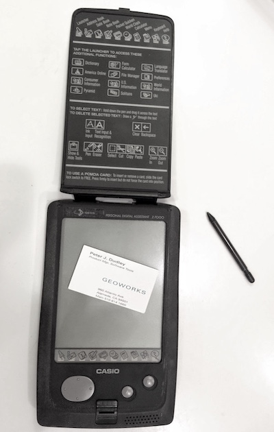 A Casio Z-7000 PDA opened to show the screen and stylus, with Peter's business card from 1996 on it.