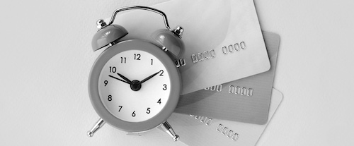 Small alarm clock lies on credit cards in black and white. concept of procrastination is just borrowed time